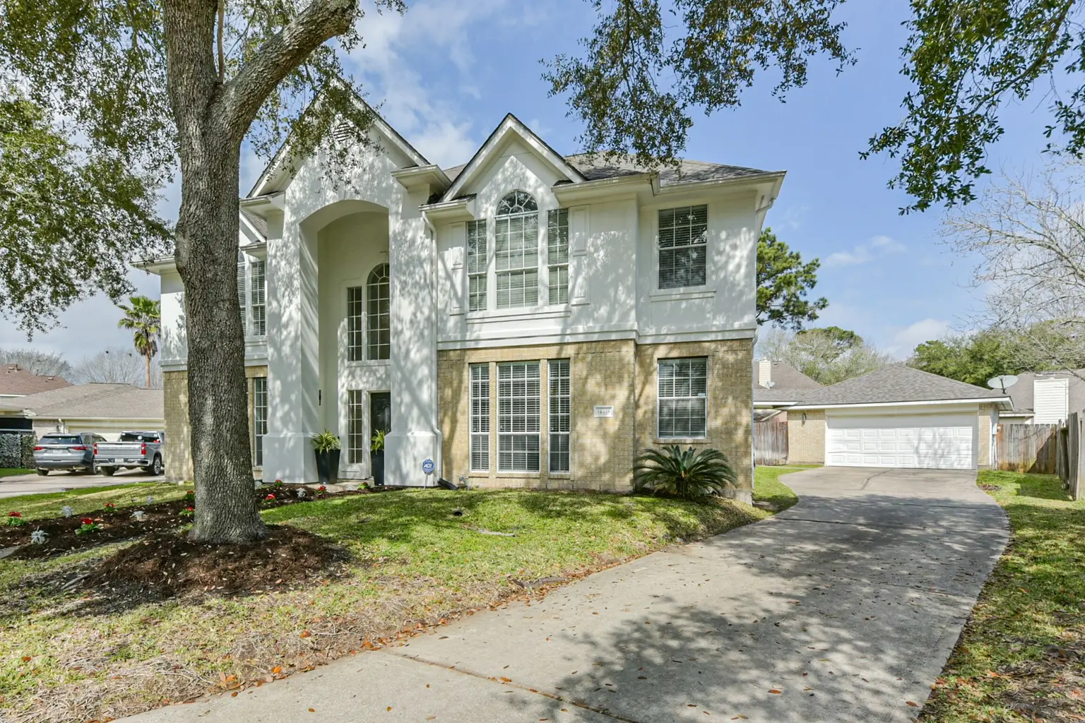 A two-story brick and stucco home photographed in flat midday daylight