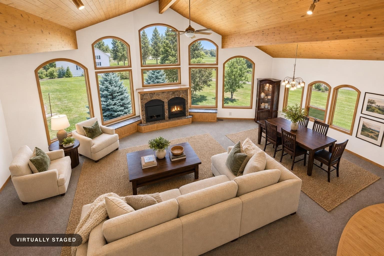 Luxury living room with large arched windows, a beige sectional sofa, two armchairs, wooden coffee and dining tables, and vaulted wood ceiling.