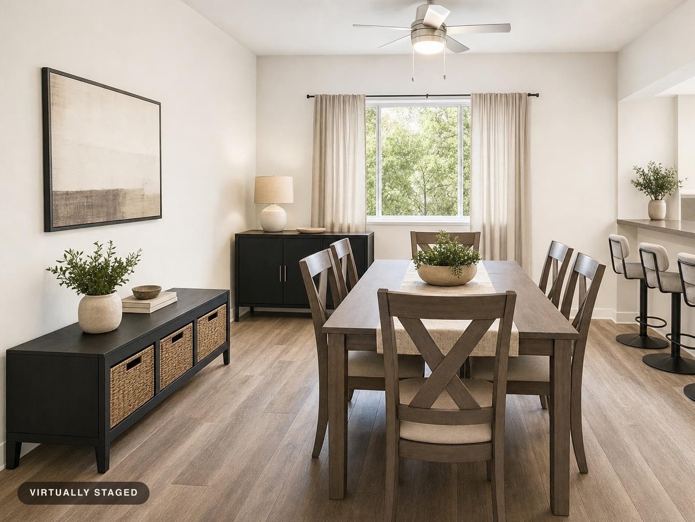 Modern dining room with wood table, six chairs with fabric cushions, black sideboards with baskets, and a ceiling fan above.