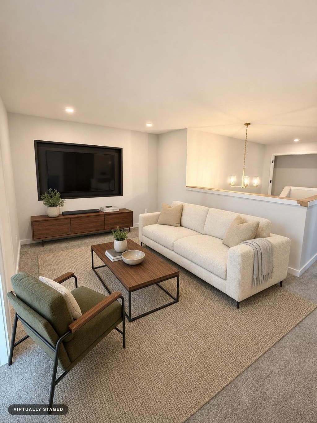 Modern living room with cream sofa, green armchair, wooden coffee table and media console, and neutral rug.