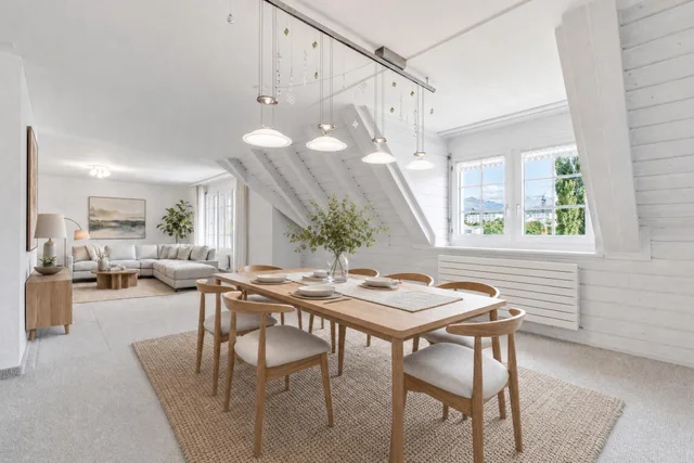 Scandinavian dining room with wooden table and chairs, pendant lights, and a large woven rug under the table.
