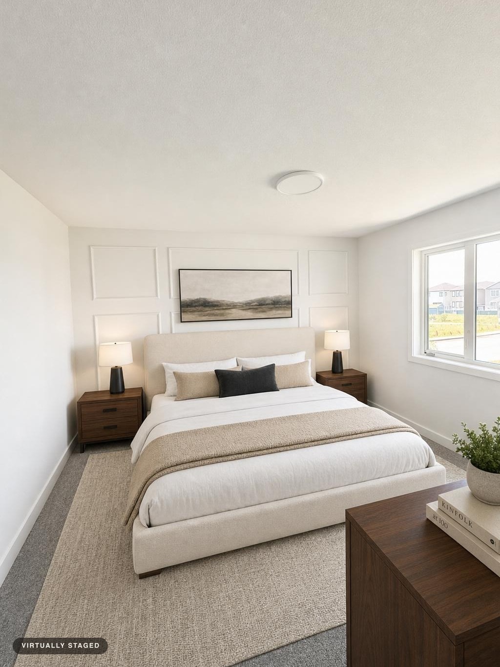 Modern bedroom with beige upholstered bed, two wood nightstands with black lamps, a window, and a wooden dresser with books and a plant.