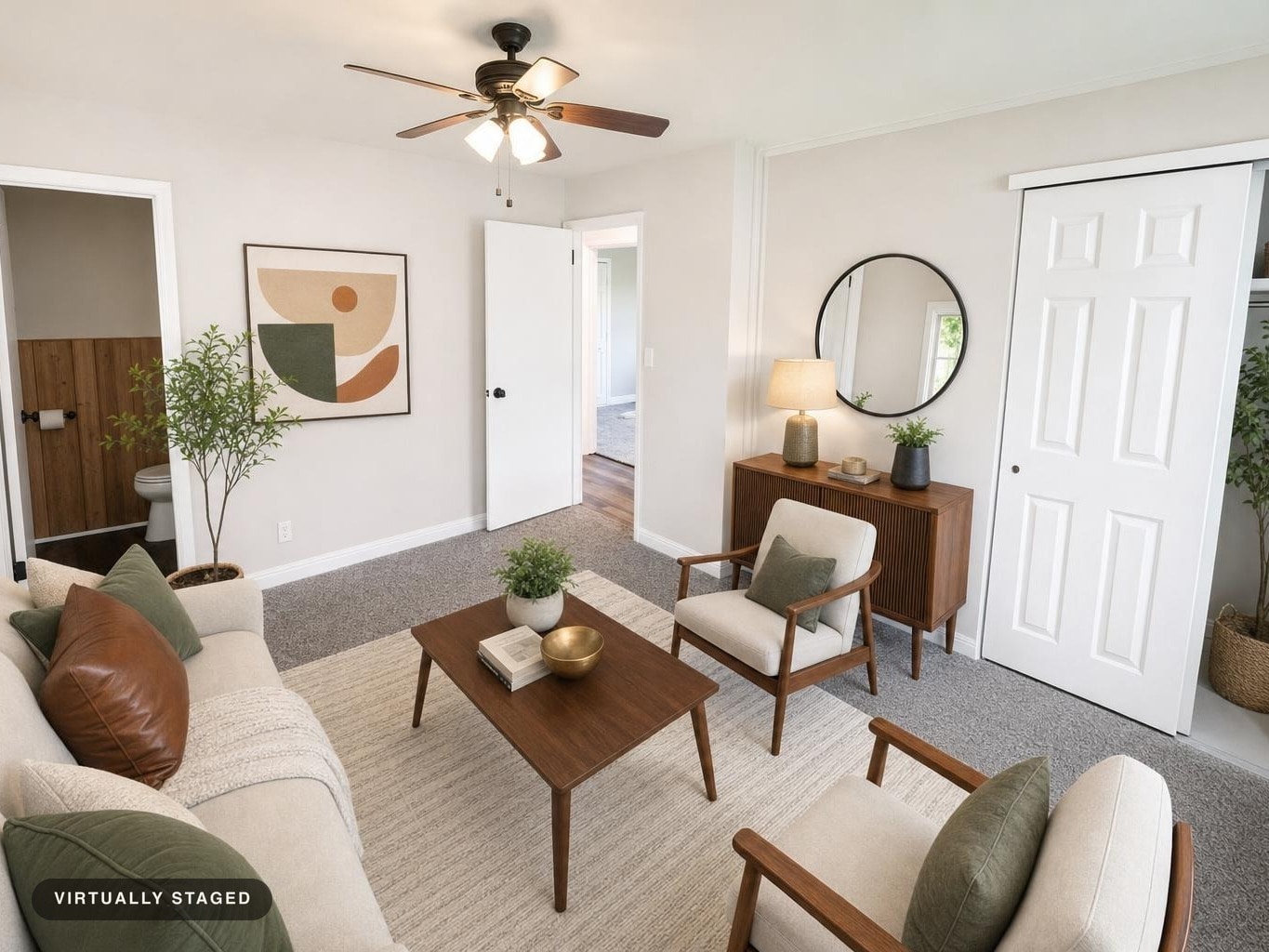 Living room with beige sofa and chairs, wooden coffee table, sideboard, and abstract wall art in a neutral midcentury style.