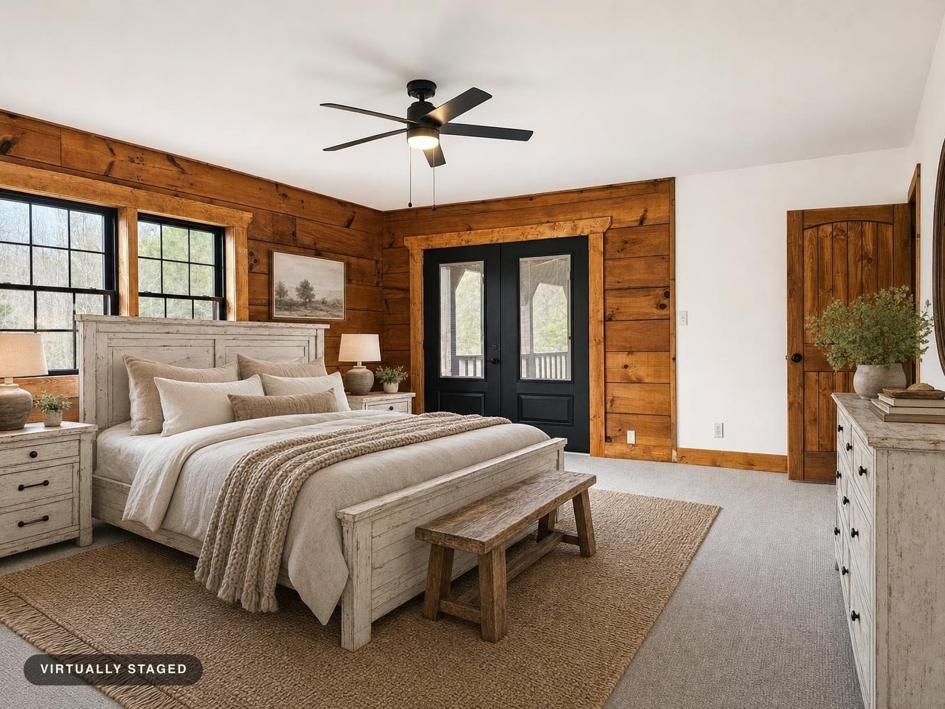 A rustic modern bedroom with distressed white wood bed and furniture, a wooden bench, jute rug, and black framed French doors.