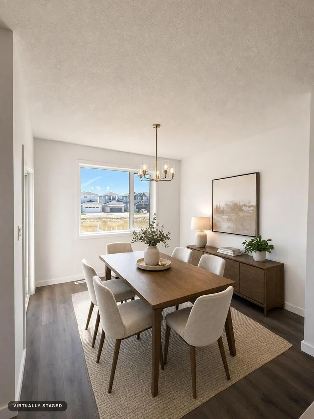 Modern dining room with wood dining table, six beige upholstered chairs, sideboard with lamp and plant, and chandelier.