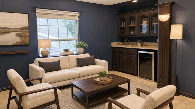 Living room with cream sofa, two matching armchairs, dark wood coffee table, navy blue walls, and built-in cabinetry with granite countertop.
