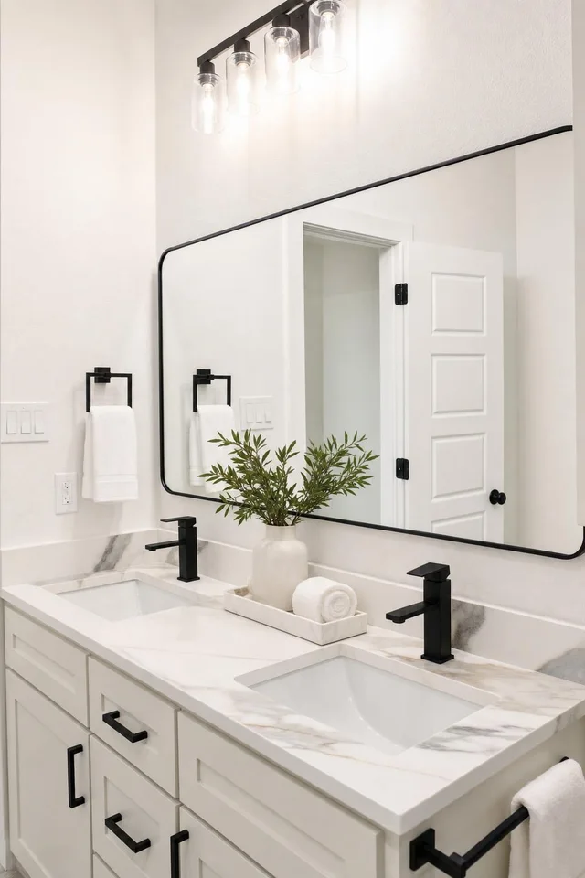 A modern double-sink bathroom vanity with white and gray marble countertop, black faucets, and a large rectangular mirror.