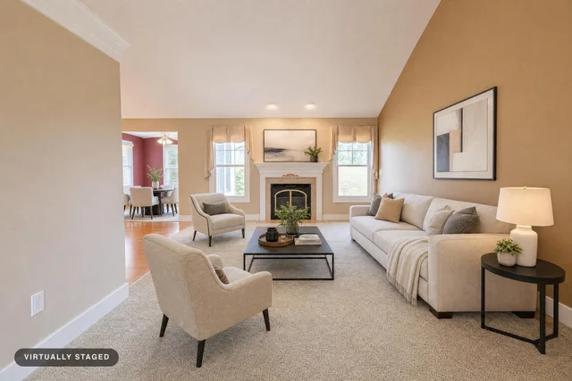 Modern living room with beige sofa, two matching armchairs, a black coffee table, and a fireplace with artwork above.