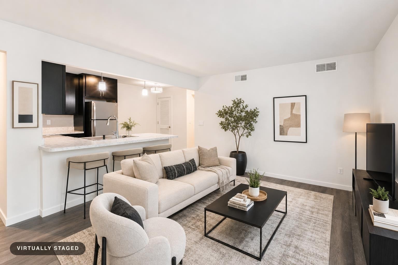 Modern living room with beige sofa, round armchair, black coffee table, bar stools, floor lamp, and abstract wall art.