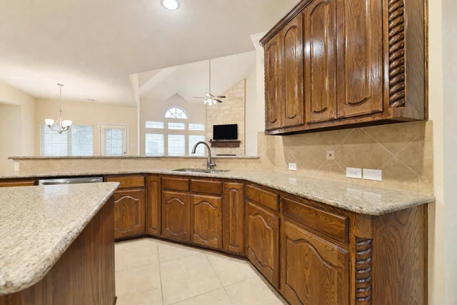 Kitchen interior featuring dark wood cabinets and granite-look countertops with beige tile backsplash and floor.