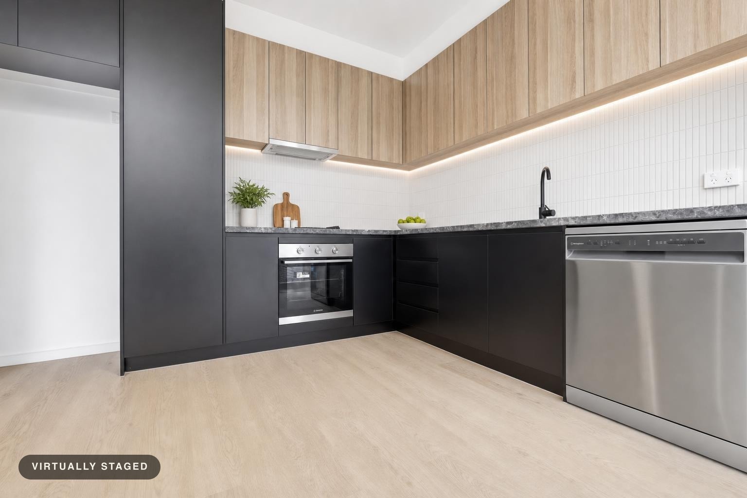 Modern kitchen with black lower cabinets, light wood upper cabinets, black faucet, and stainless steel oven and dishwasher.
