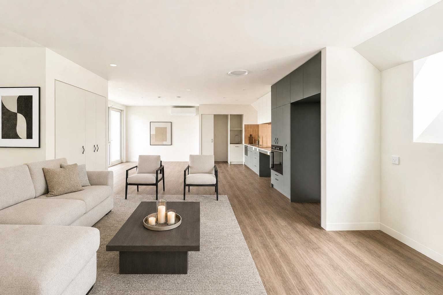 Bright modern living room with beige sofa, two beige armchairs, dark wooden coffee table, and light wood floor.