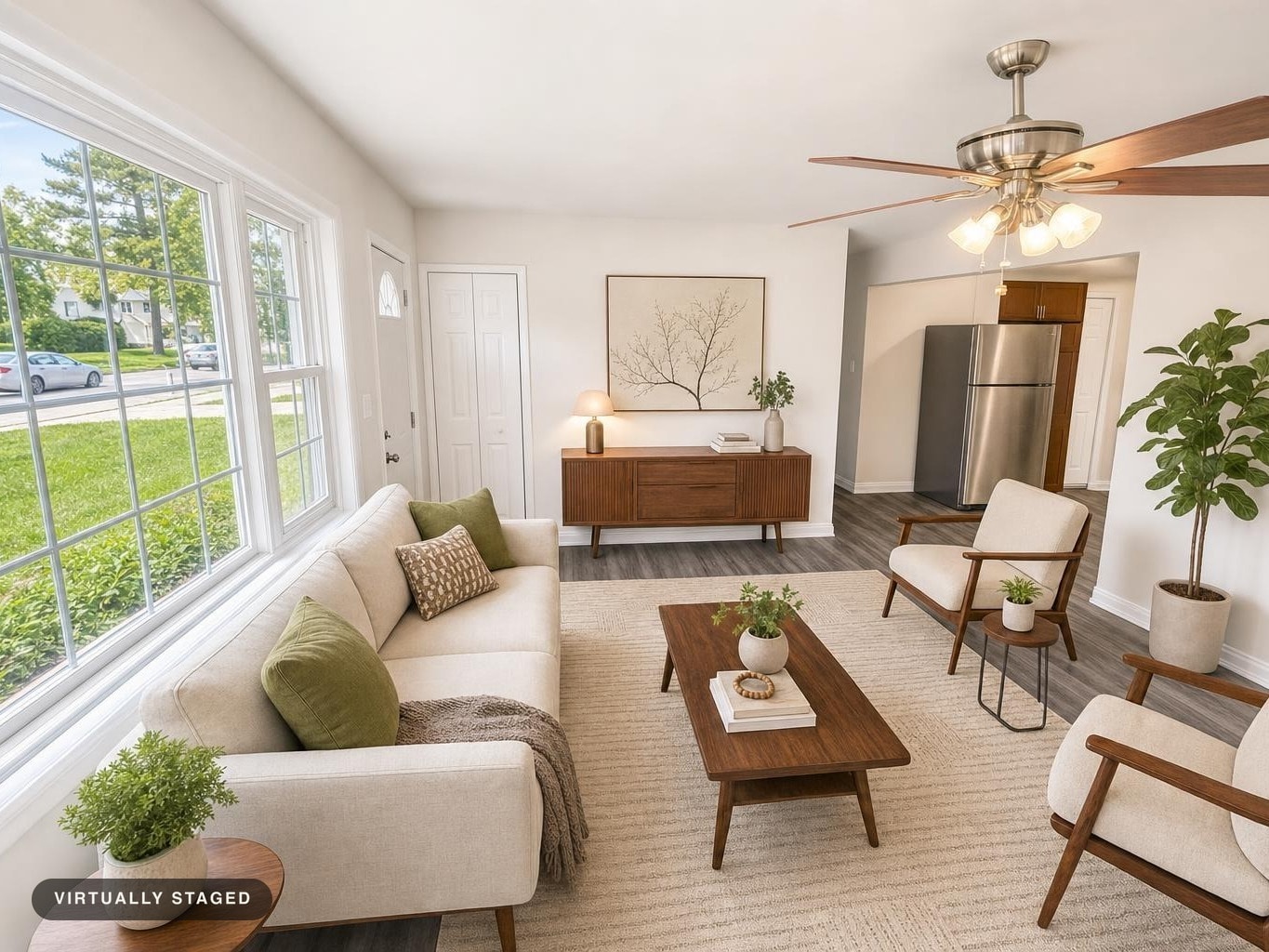 Bright living room with cream sofa, midcentury wood furniture, green cushions, indoor plants, and ceiling fan with wood blades.