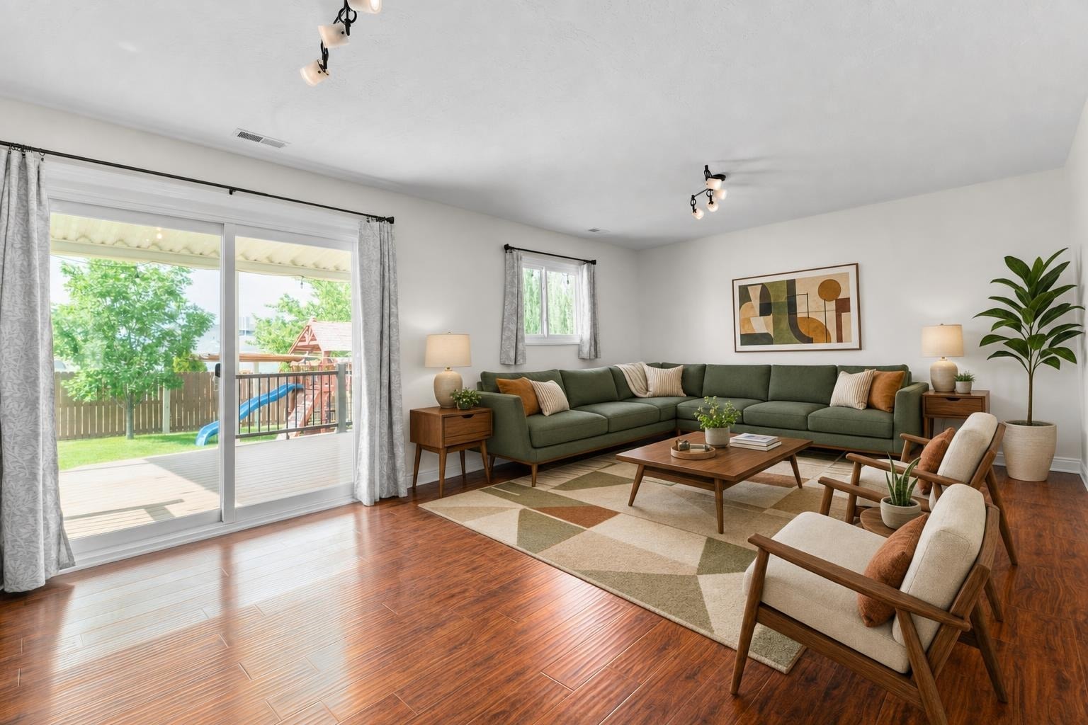Midcentury living room with green sectional sofa, two wood framed chairs, geometric rug, wooden coffee table, and sliding glass doors.