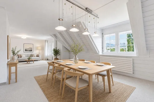 Light-filled Scandinavian dining room with wooden table, six chairs, jute rug, and a bright living area beyond.