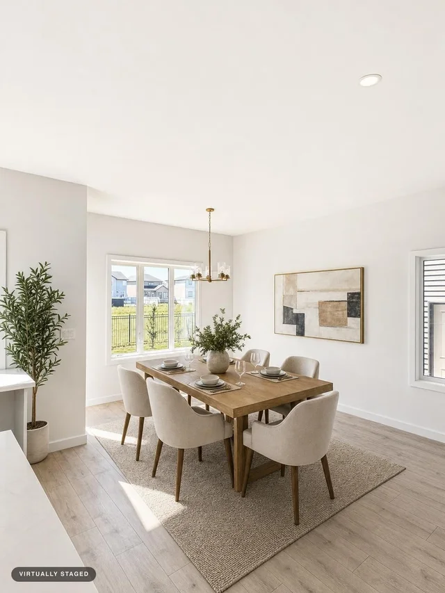 A bright dining area with a wooden table, six creamy upholstered armchairs, a textured rug, and a geometric art piece on the wall.