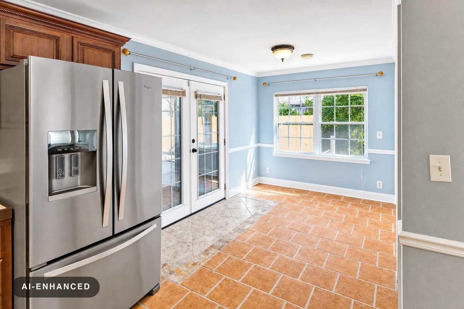 Kitchen area with stainless steel refrigerator, blue walls, terracotta floor tiles, and glass double doors to outside.