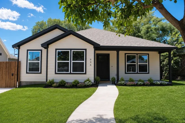 Modern single-story beige house with black trim, three front windows, black door, and a winding concrete sidewalk through green grass.