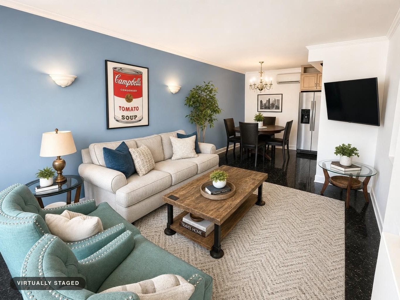 Living room with blue wall, beige sofa, teal armchairs, wooden coffee table, glass side table, and dining area in background.