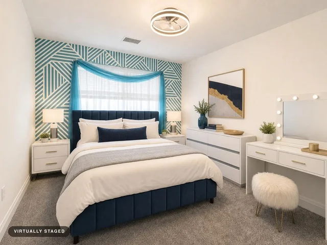 Modern bedroom with a navy upholstered bed in front of a blue and white geometric patterned accent wall, white furniture, and carpeted flooring.