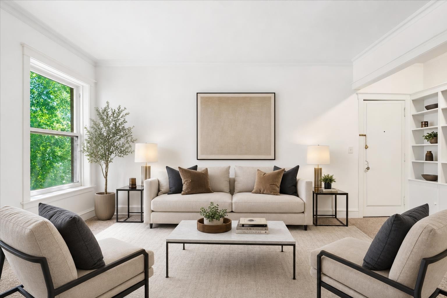 Modern living room with beige sofa and armchairs, black metal side tables and coffee table, plants, and large window.