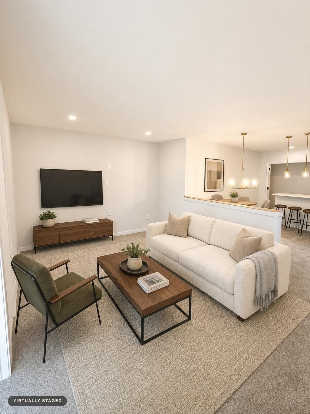 Modern living room with white sofa, olive chair, wood coffee table, media console, and wall-mounted TV on a beige carpet.