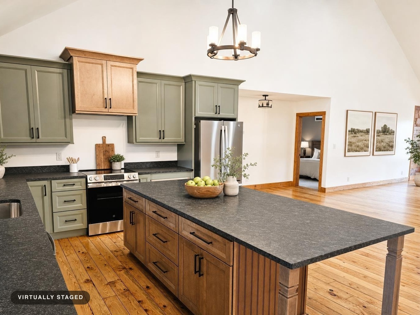 Kitchen featuring sage green upper cabinets, natural wood lower cabinets, black countertops, and a large central island with wood paneling.