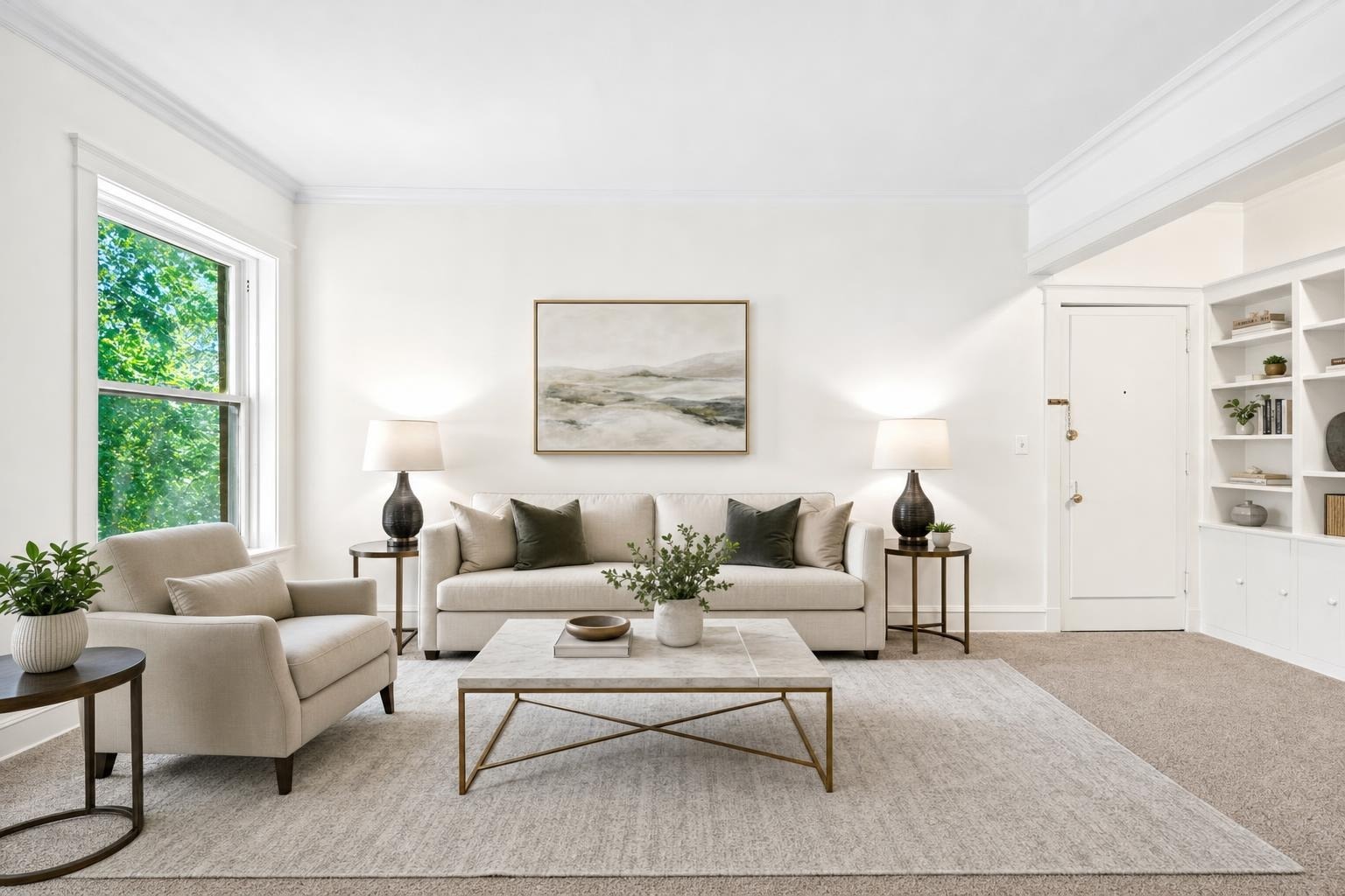 Bright modern living room with beige sofa and armchair, dark wood tables, a large neutral rug, and a landscape painting on the wall.