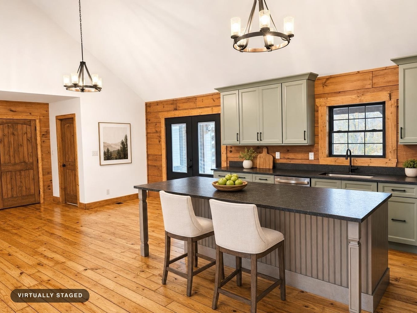 Kitchen with sage green cabinets, black granite countertop island, wooden floor, and warm wood walls.