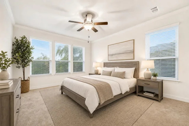 Modern bedroom with wooden bed frame, beige bedding, two nightstands with lamps, and a dresser with plants.