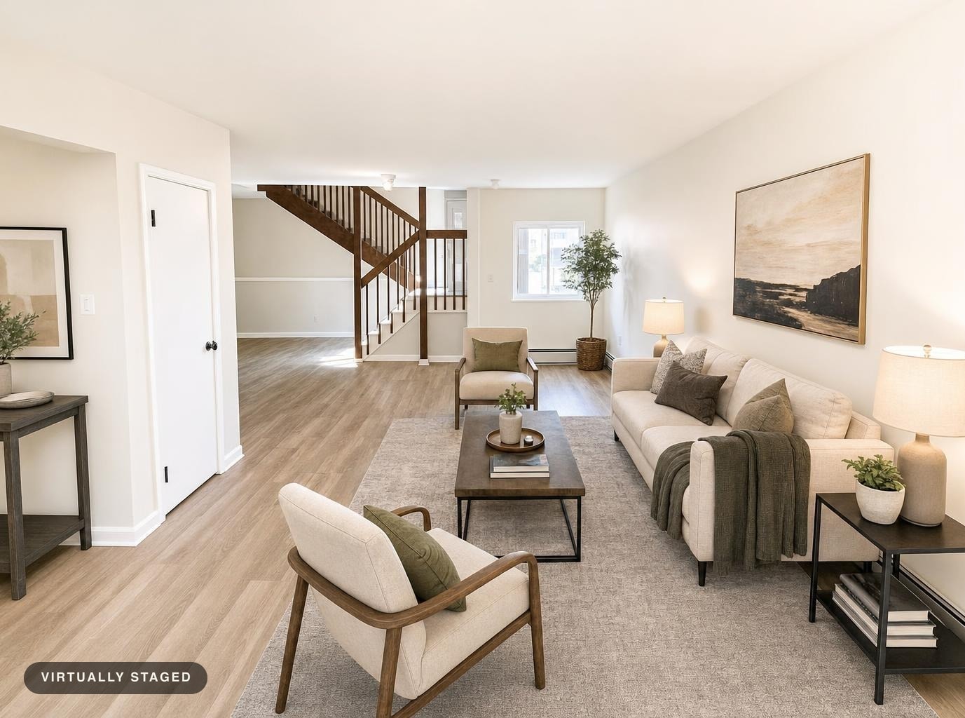Modern living room with beige sofa, two beige armchairs, wooden coffee table, and natural wood stair railing.