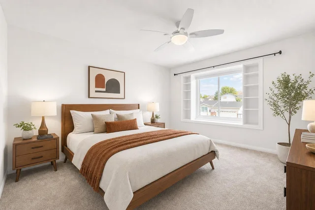 Midcentury bedroom with wooden platform bed, two matching nightstands with lamps, abstract wall art, and a large window.
