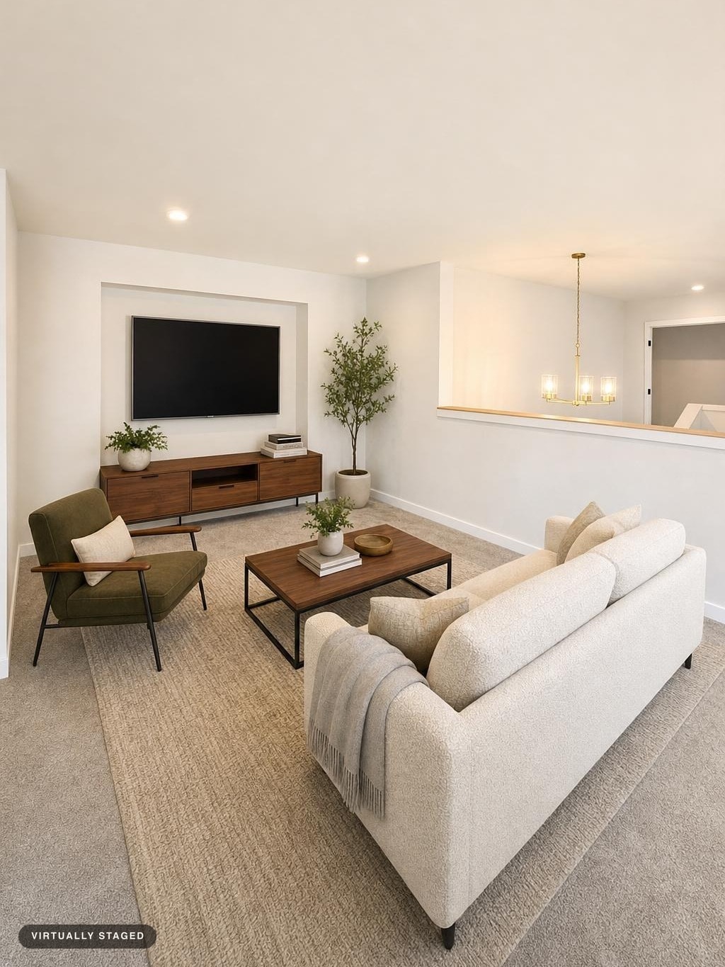 Modern living room with beige sofa, green armchair, wooden media console, wood and metal coffee table, and neutral rug.