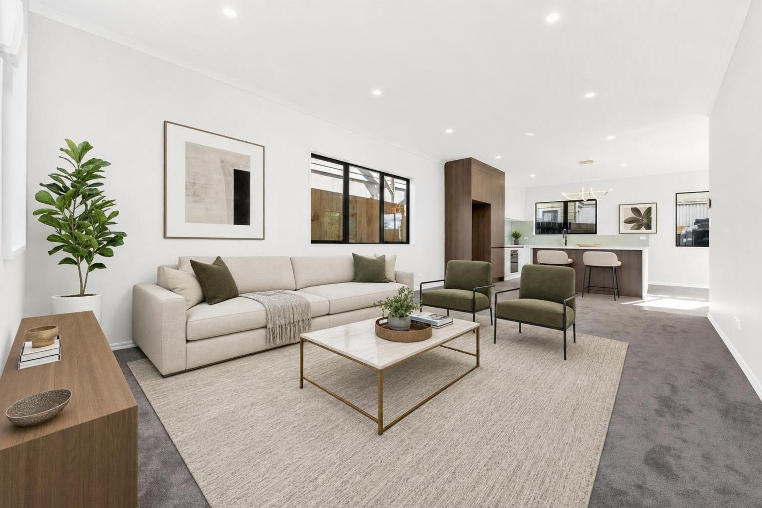 Modern living room with beige sofa, two olive green armchairs, a marble-look coffee table with gold frame, and wooden sideboard with plant.