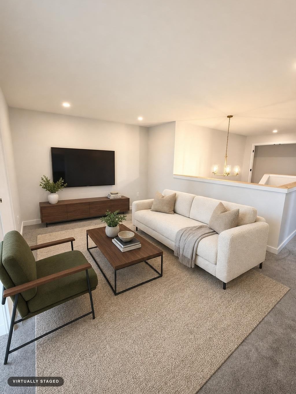 Modern living room with ivory sofa, olive armchair, wooden coffee table, wooden TV stand, neutral rug, and wall-mounted TV.