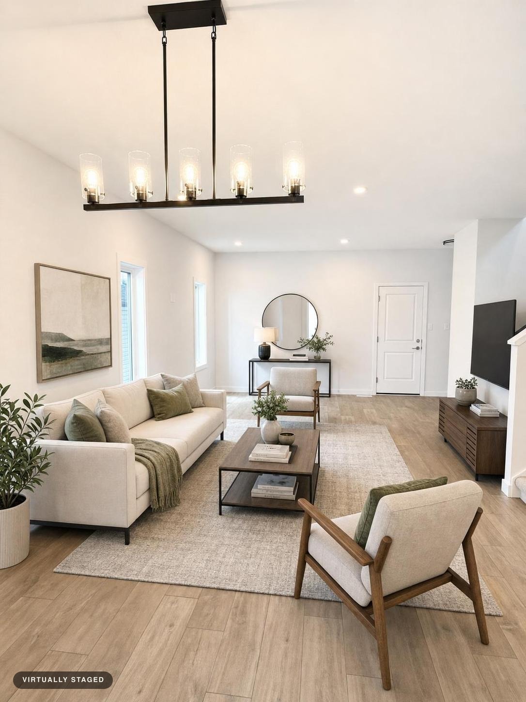 Bright modern living room with beige sofa, wood framed armchair, wooden coffee table, and modern light fixture.