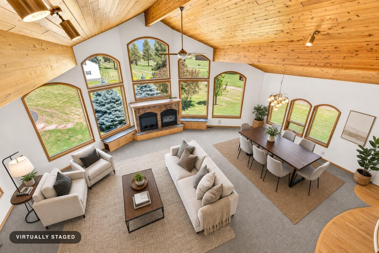 Spacious living room with vaulted wood ceiling, large arched windows, beige sofa and armchairs, wooden coffee and dining table with beige chairs.