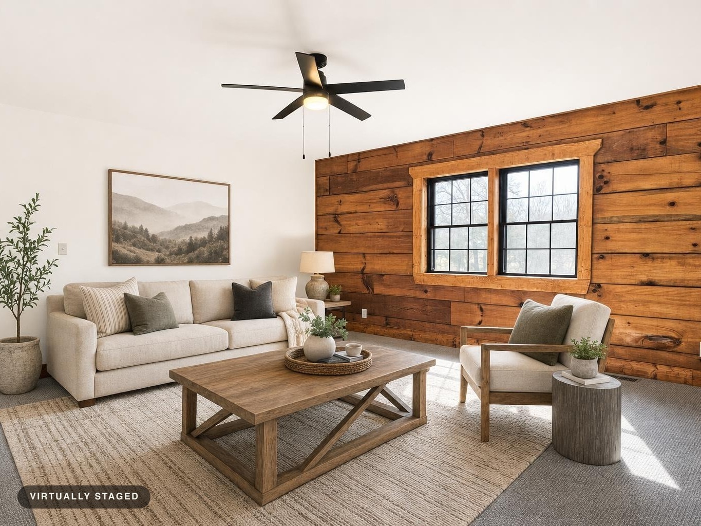 Living room with beige sofa and armchair, wooden coffee table, rustic wood wall, and ceiling fan with light.