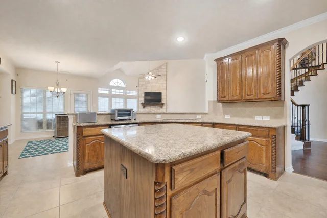 Kitchen with traditional wooden cabinets, granite countertops, large island, and built-in oven.