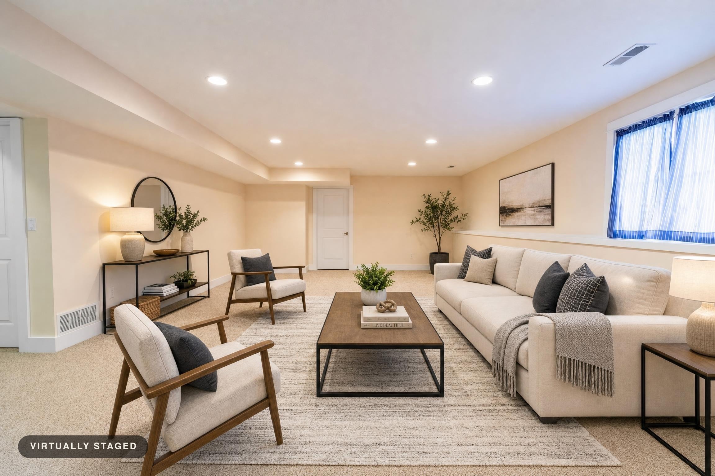 Modern living room with beige sofa, two armchairs, wood and metal coffee table, console and side tables, soft rug, and neutral decor.
