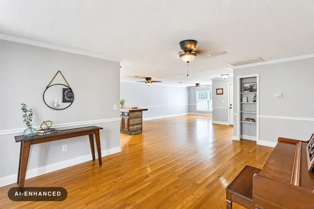 Bright living room with light gray walls, hardwood floors, a wooden console table with decor, and a piano on the right.