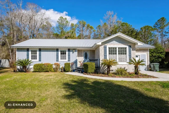 Single-story house with light blue siding and white trim, metal roof, front steps, lawn, and palm plants under a blue sky.