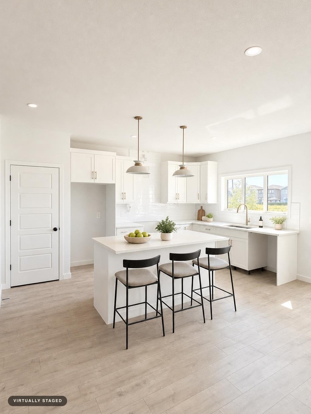 Modern white kitchen with island, three black-framed stools, white cabinets, pendant lights, and light wood flooring.