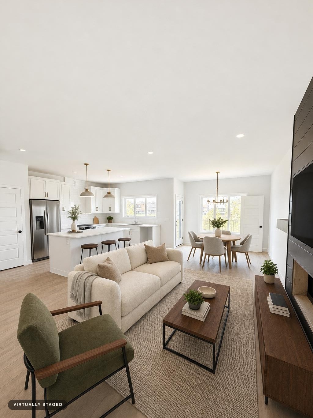 Modern living room with beige sofa, olive green armchair, wooden coffee table, media console, and dining area with round table and chairs.