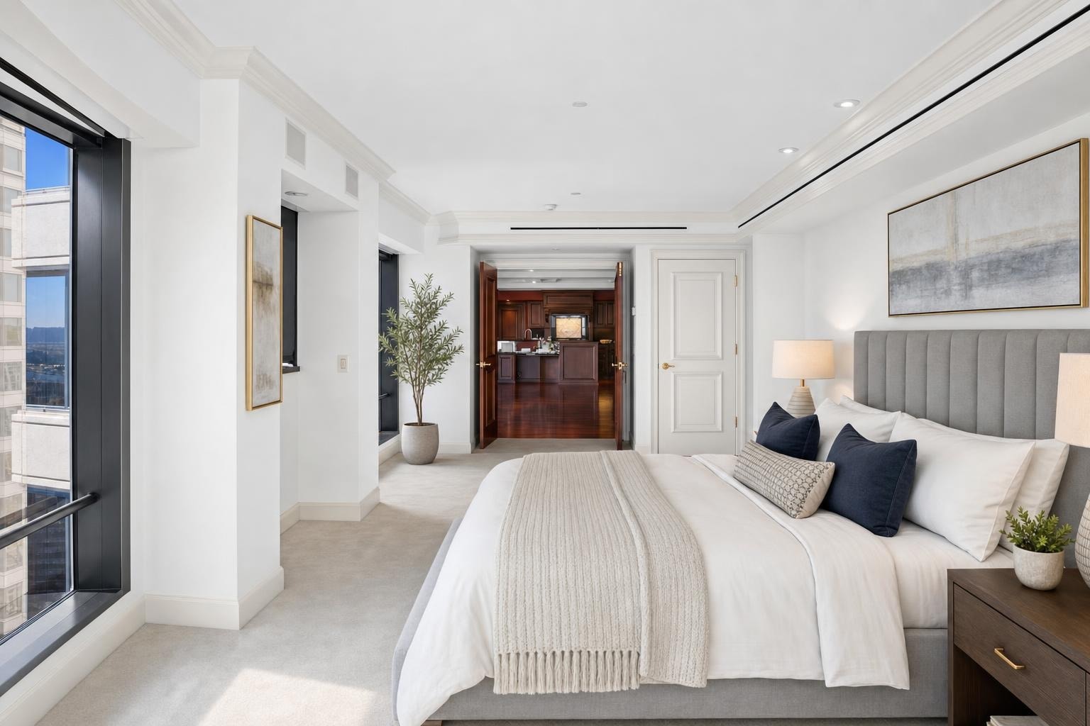 Luxury bedroom with large window, gray upholstered bed, white bedding, dark wood nightstand, and table lamps.