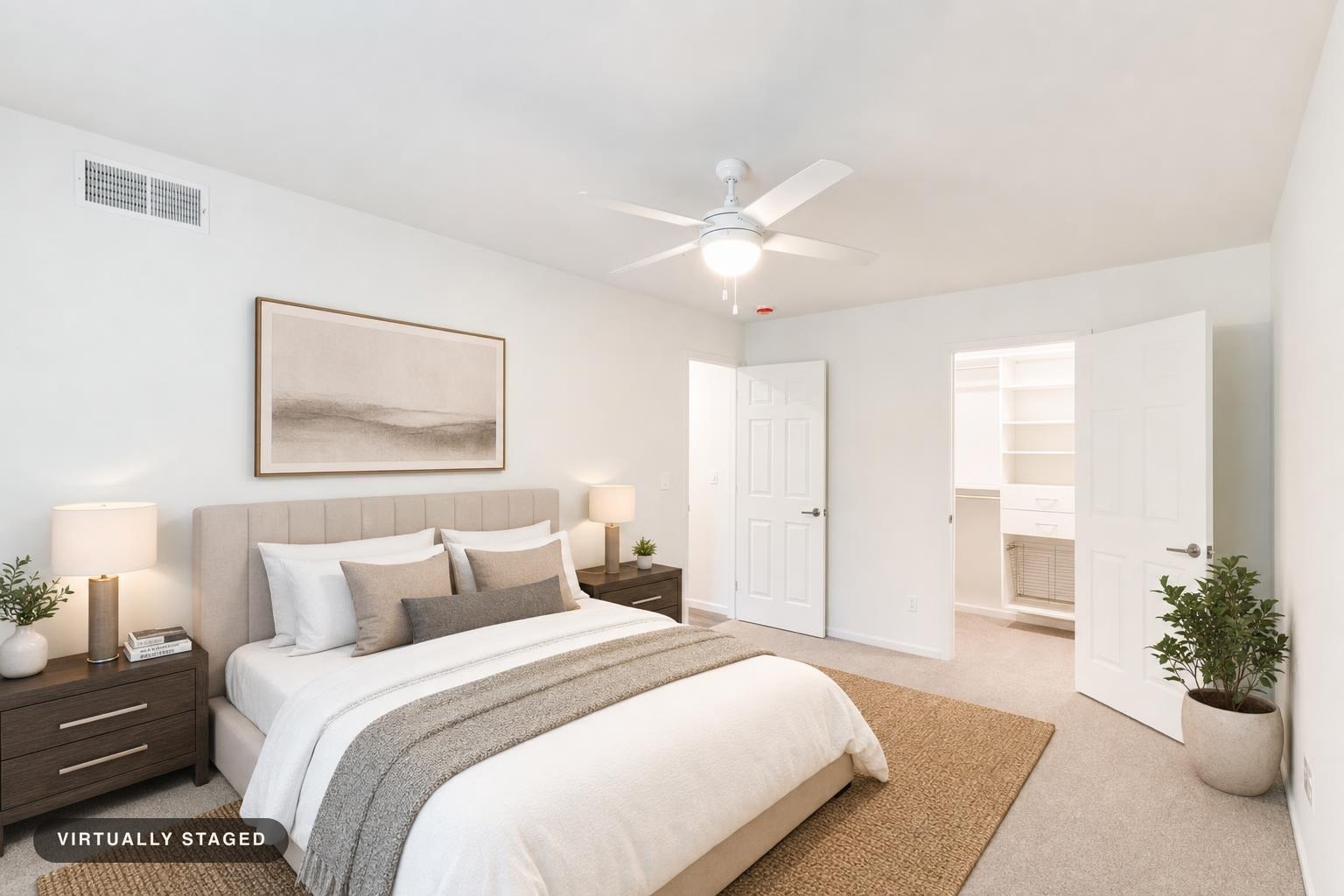 Modern bedroom with beige upholstered bed, white bedding, dark wood nightstands with lamps, and a plant near open doors.