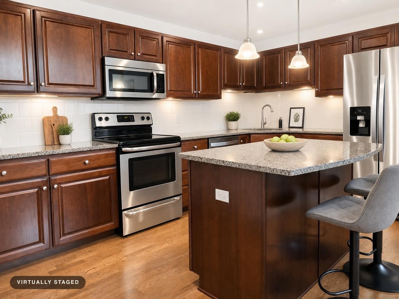 Modern kitchen with dark wood cabinets, stainless steel oven and fridge, granite-look island with two gray upholstered bar stools.