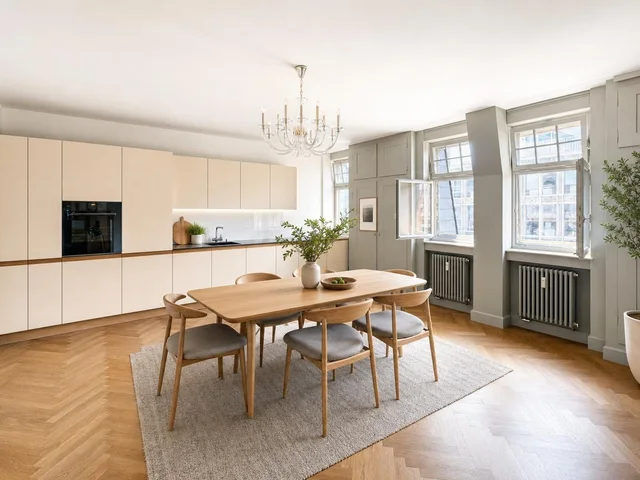 Scandinavian dining room with light wood table, six chairs with gray cushions, beige cabinetry, parquet floor, and large windows.