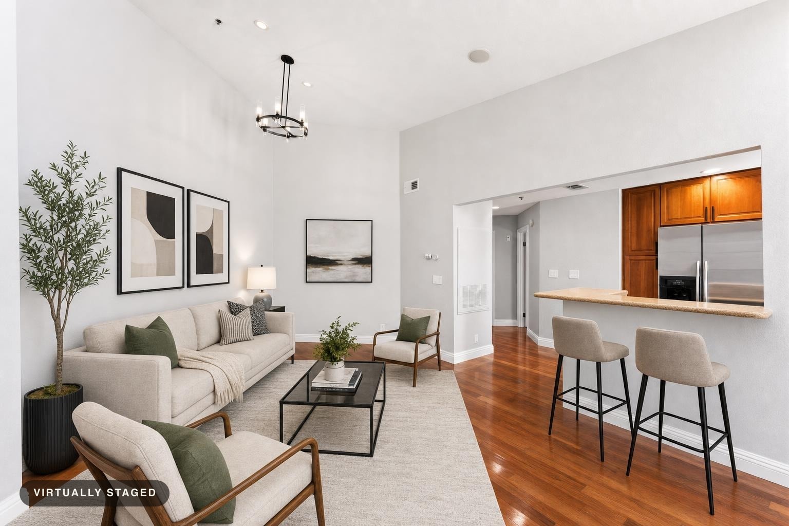 Modern living room with light beige sofa, two armchairs, black metal coffee table, and kitchen breakfast bar with two stools.