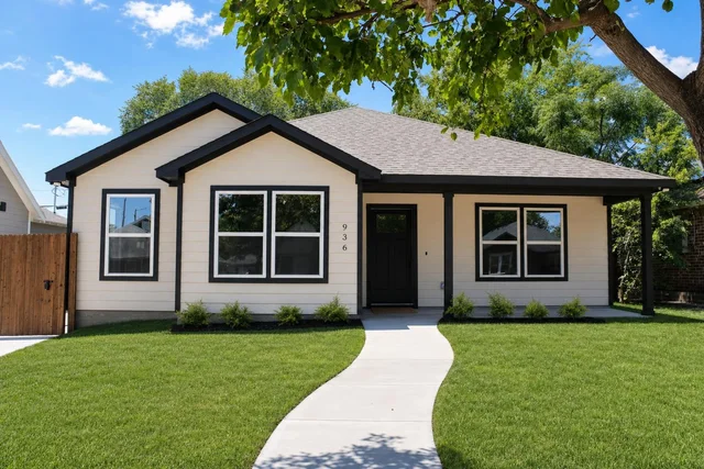 Single-story house with beige siding, black trim, black front door, three double-pane windows, front yard with green lawn and small shrubs.